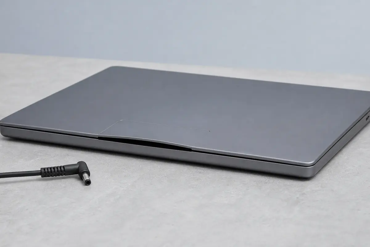 Geschlossener Laptop mit angehobenem Gehäuse und getrenntem Ladekabel