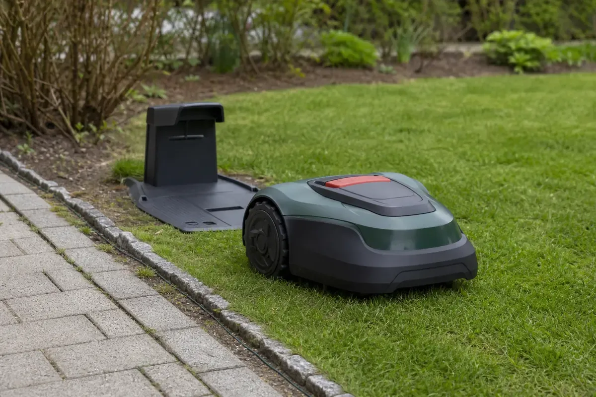 Grüner Mähroboter neben einer Ladestation und einem Begrenzungskabel